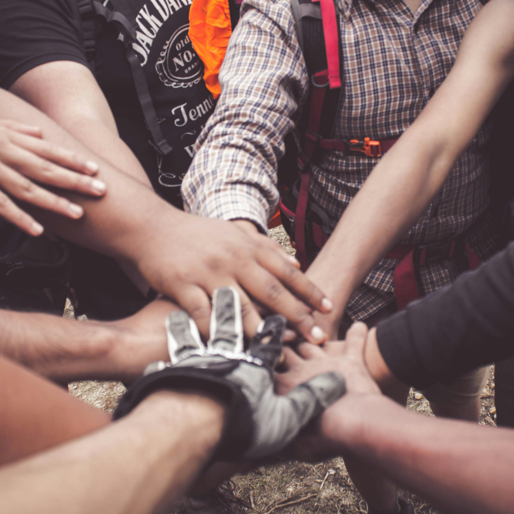 Group of people with hands stacked together outdoors